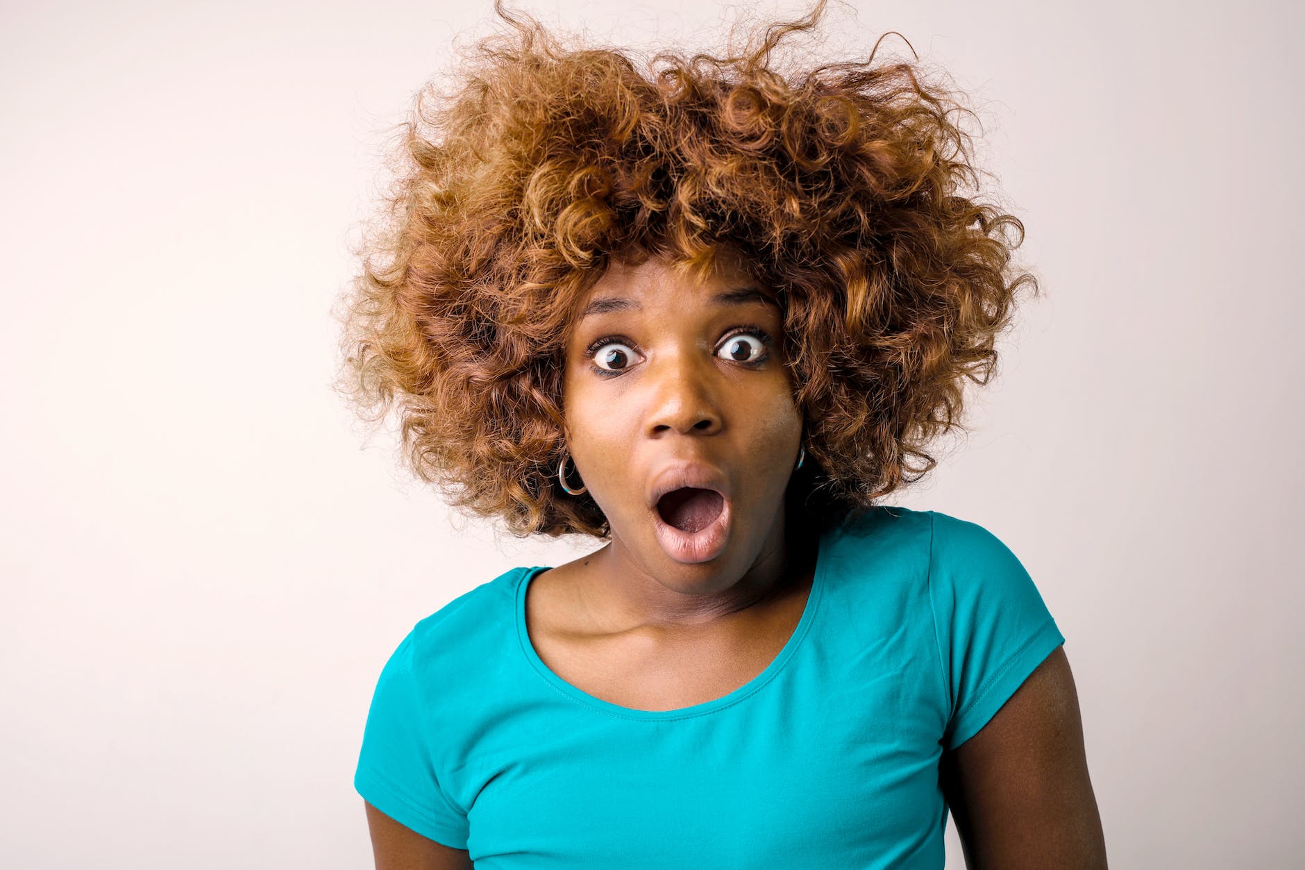 portrait photo of shocked woman in blue t shirt standing in front of white background
