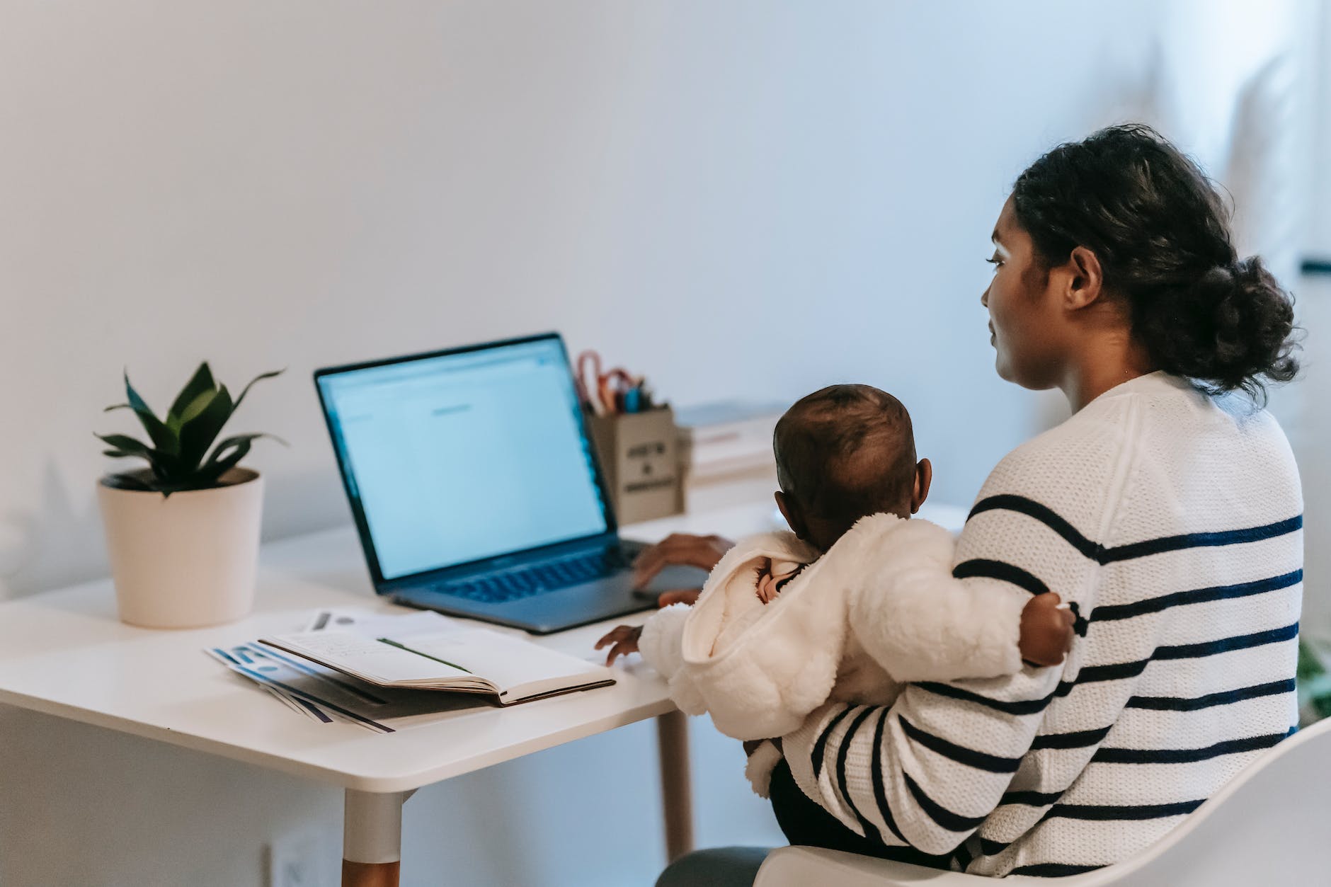 mother carrying her baby while working from home